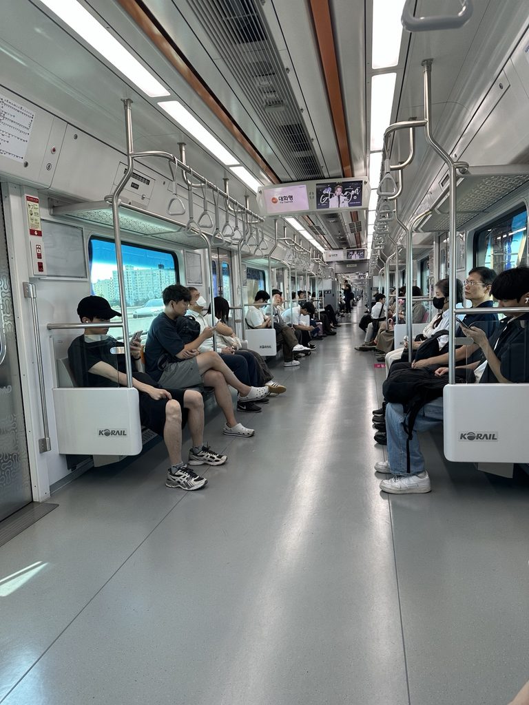 Inside a Seoul subway train with passenger seating and hand straps