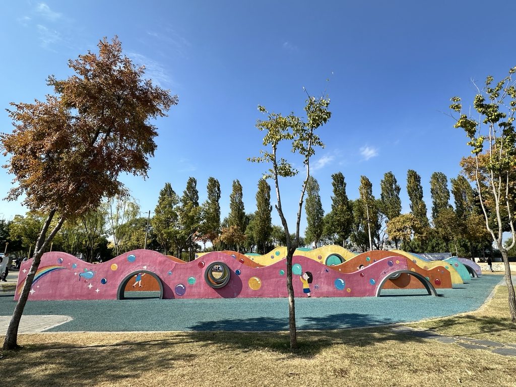 Colorful outdoor children's play structure with tunnels and climbing features at Banpo Hangang Park in Seoul.