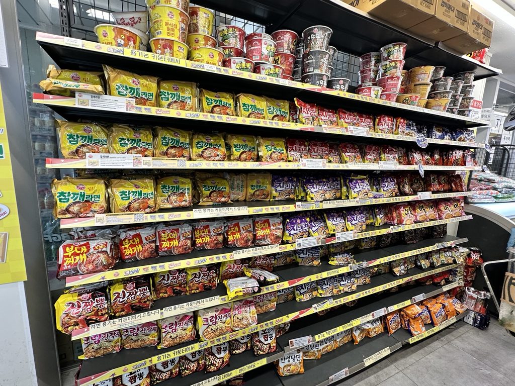 Shelves stocked with Korean instant ramen, including Shin Ramyun and Chamkkae Ramen, at a convenience store in Banpo Hangang Park, Seoul.