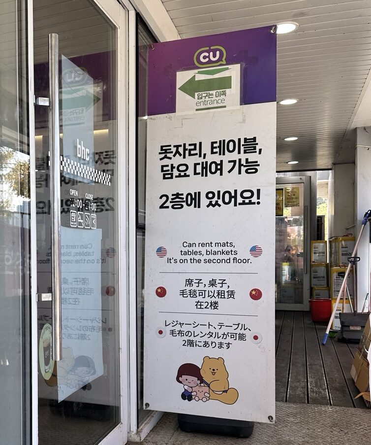 Multilingual sign at Banpo Hangang Park CU convenience store showing picnic mat, blanket, and table rentals on the second floor