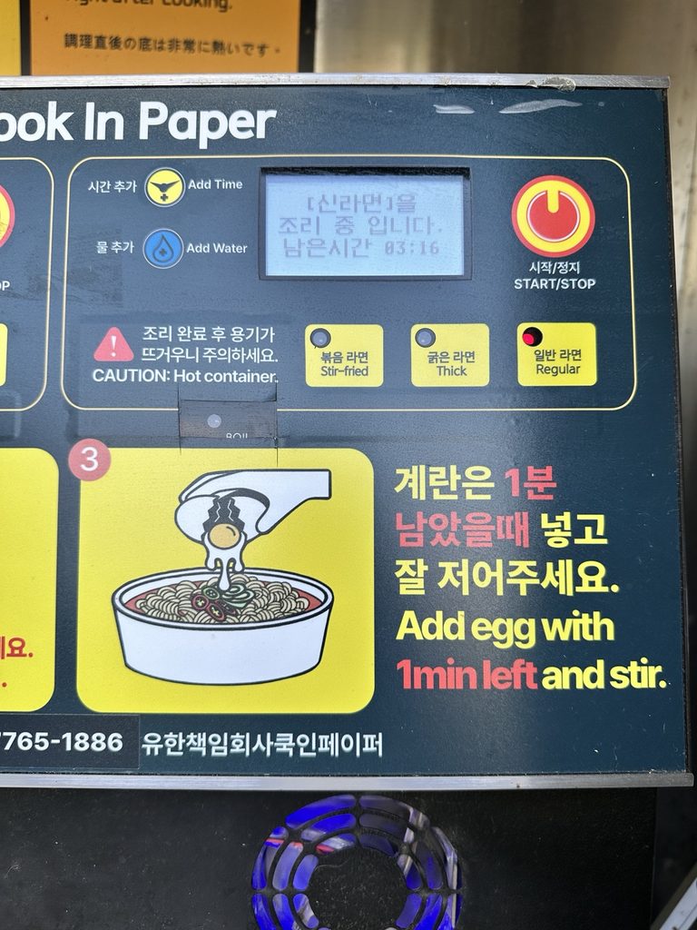Close-up of a Han River ramen cooking machine showing stir-fried, thick noodle, and regular ramen settings, plus instructions for adding an egg with one minute left.